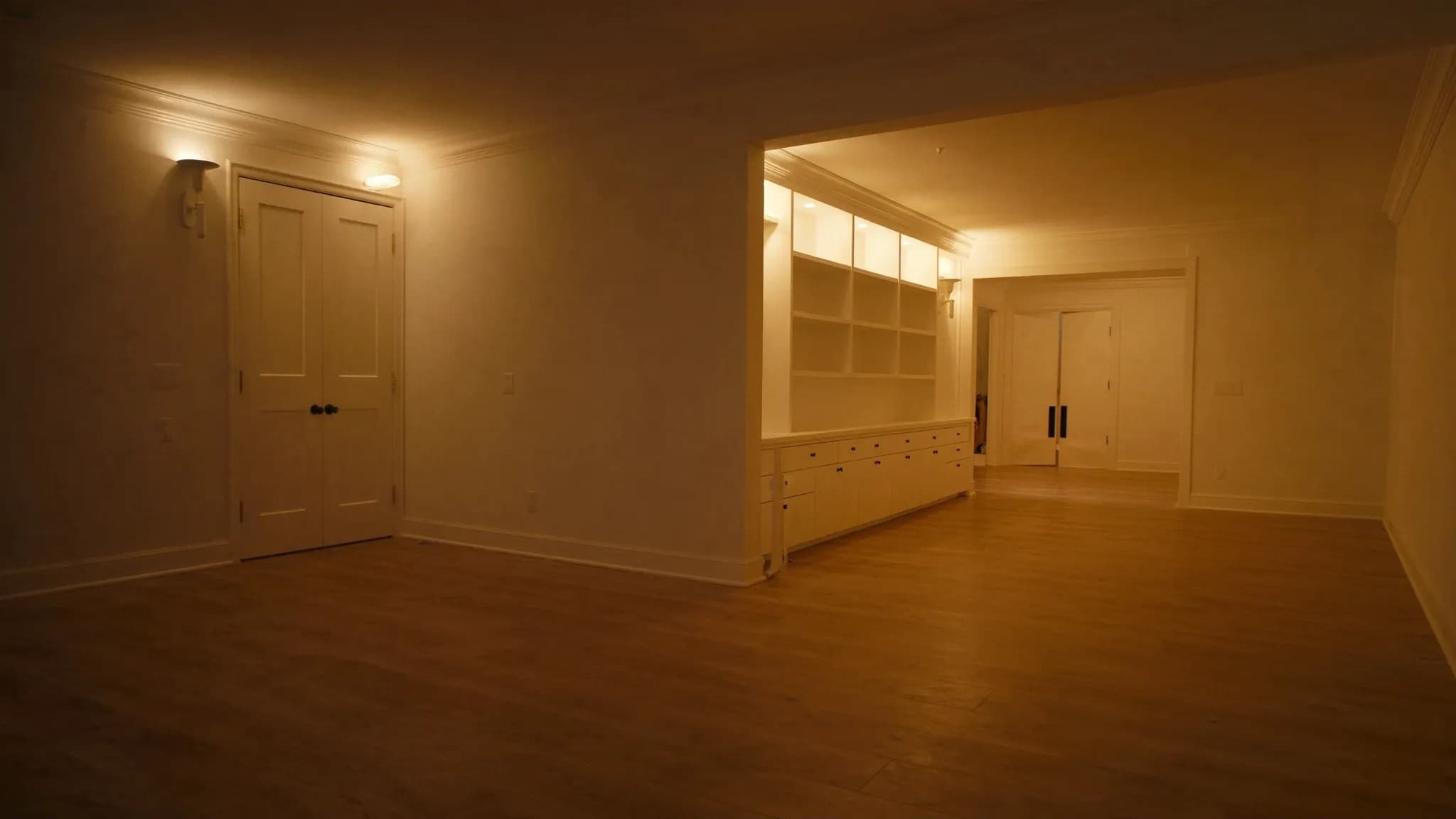A finished room lit evenly by recessed cans and wall sconces at dusk